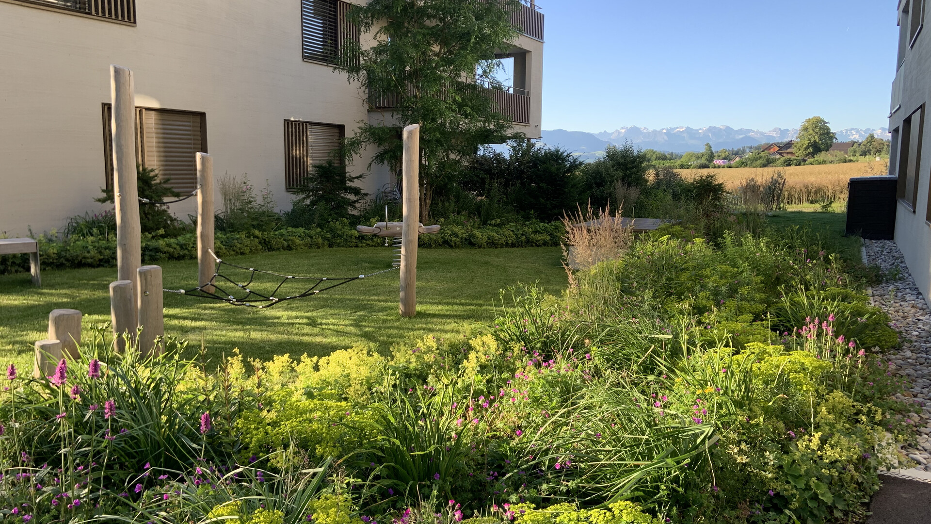 Spielgeräte aus Holz mit Staudenrabatte im Garten