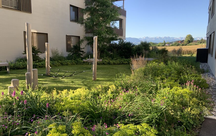 Spielgeräte aus Holz mit Staudenrabatte im Garten