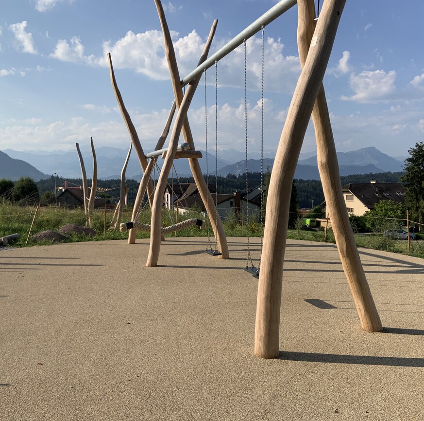 Spielplatz mit Holzgeräten auf Fallschutzbelag